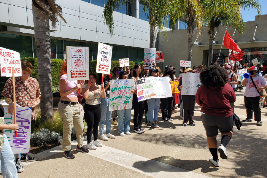 A group of people outdors at a rally with signs.