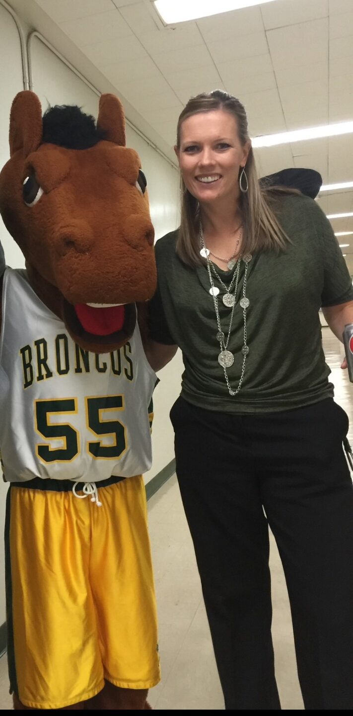 photo of school mascot Bronco in basketball uniform and woman.