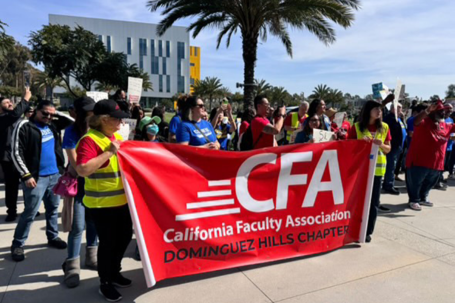 Group of members and students rallying holding a CFA banner oudoors.